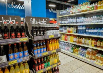 Getränkebereich im Supermarkt mit fritz-kola-Display und Regalen voller Wasser, Säfte und Softdrinks.
