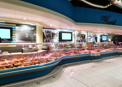 Lange Fleischtheke im Supermarkt mit Wurst- und Fleischwaren hinter Glas.