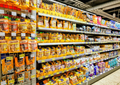 Tierfutterregal im Supermarkt mit vielen Packungen Hundesnacks und Futter.