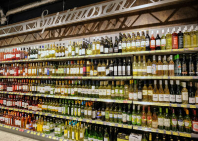 Langes Weinregal im Supermarkt mit vielen Flaschen und dem Schild „Spirituosen“.